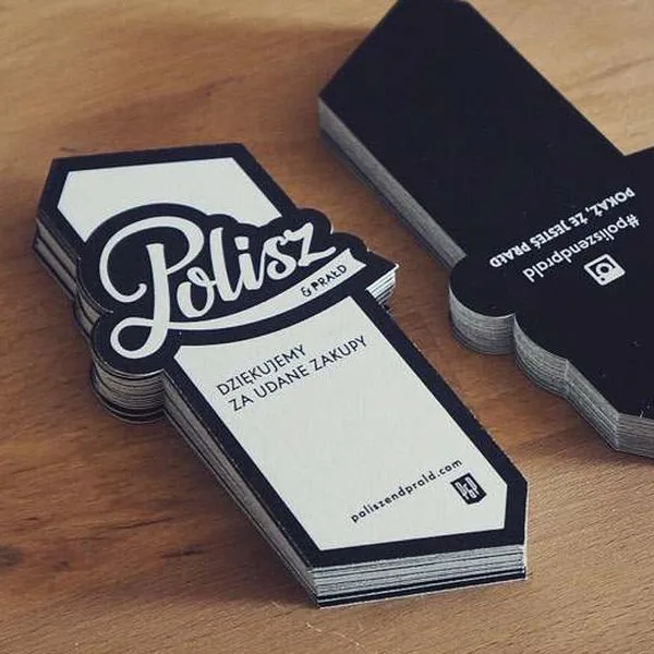 Stack of black-and-white Polisze business cards on a wooden desk.