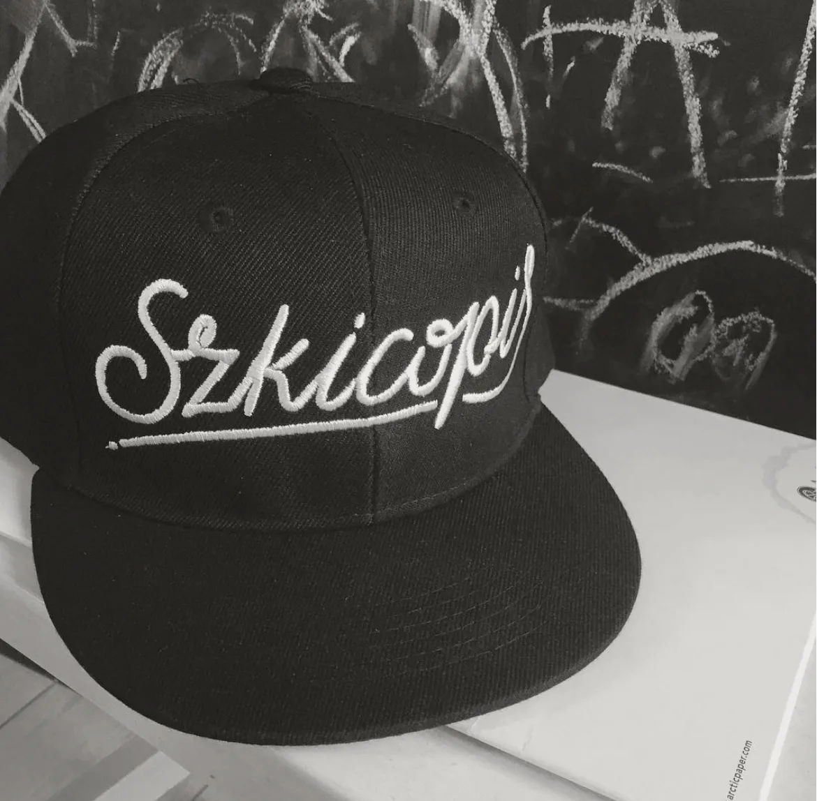 A black cap embroidered with the Szkicopis script logo.