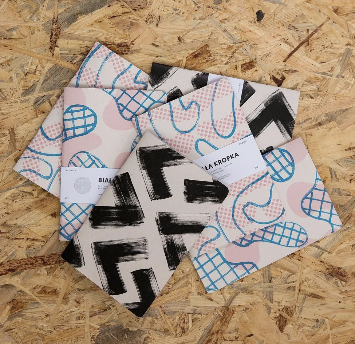 A pile of Szkicopis notebook covers in different riso-printed patterns.