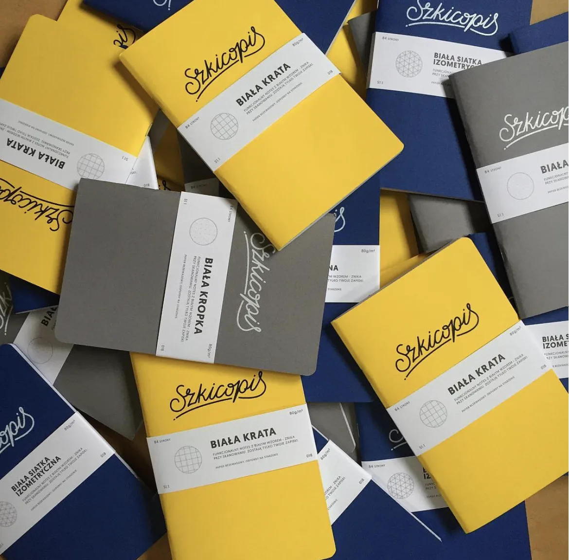 A pile of Szkicopis notebooks in yellow, navy and grey editions.
