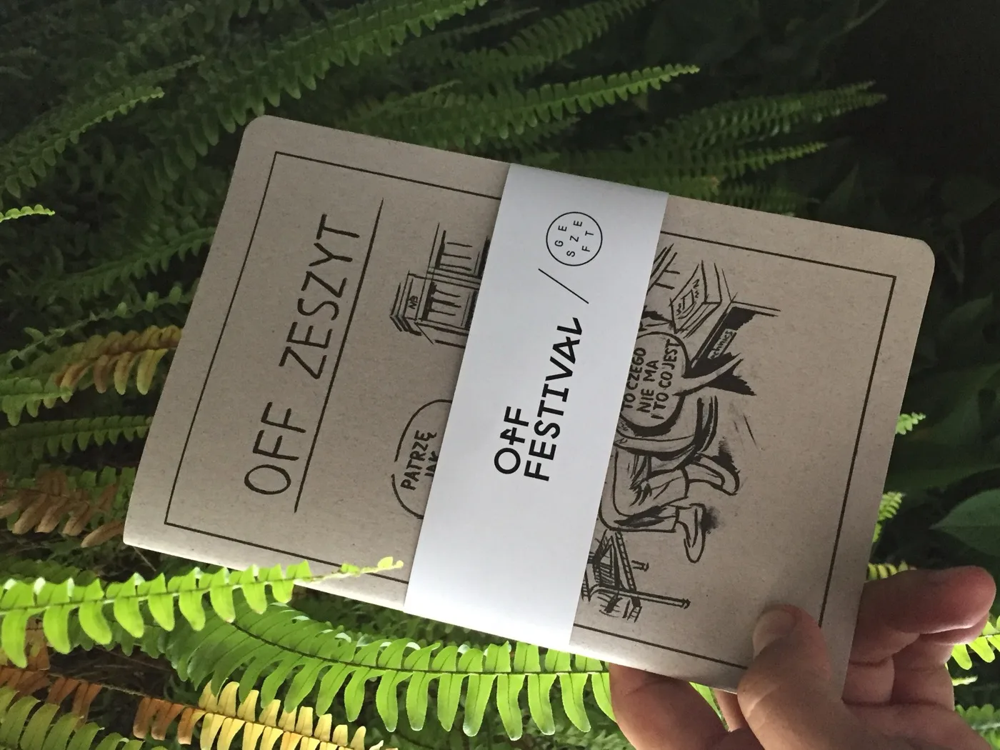 The "OFF Zeszyt" - the Szkicopis x Geszeft x OFF Festival special edition in kraft paper, held against ferns.